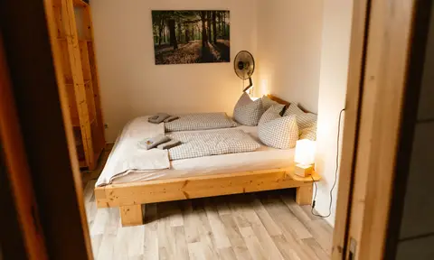 Doppelzimmer: Massivholzbett mit karierter Bettwäsche und warmem Abendlicht