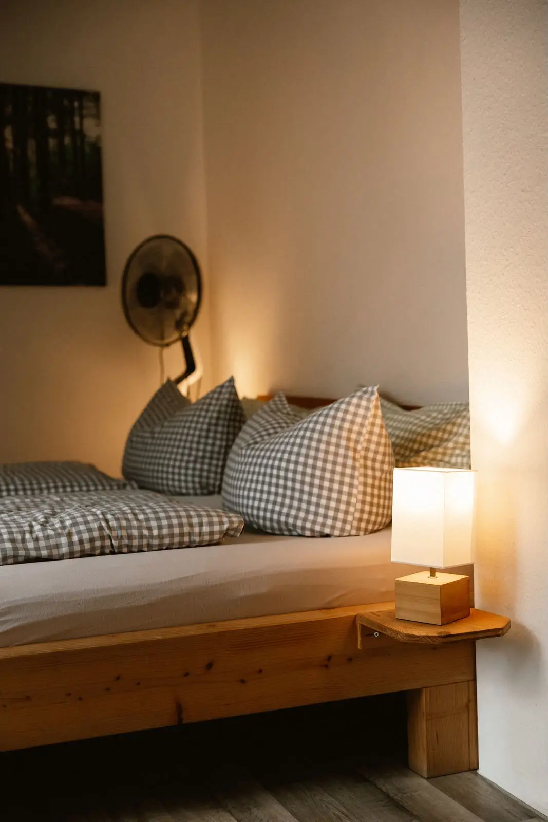 Doppelzimmer: Nachttischlampe und karierte Kissen am Bettrand