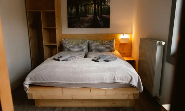 Kleines Doppelzimmer: Massivholzbett mit Kleiderschrank und warmer Leselampe