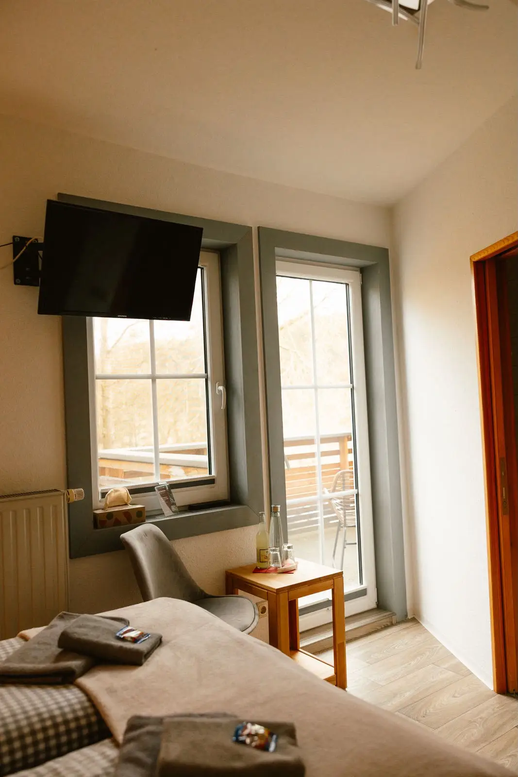 Kleines Doppelzimmer: Fernseher, Sitzecke und Fenstertür zum Balkon