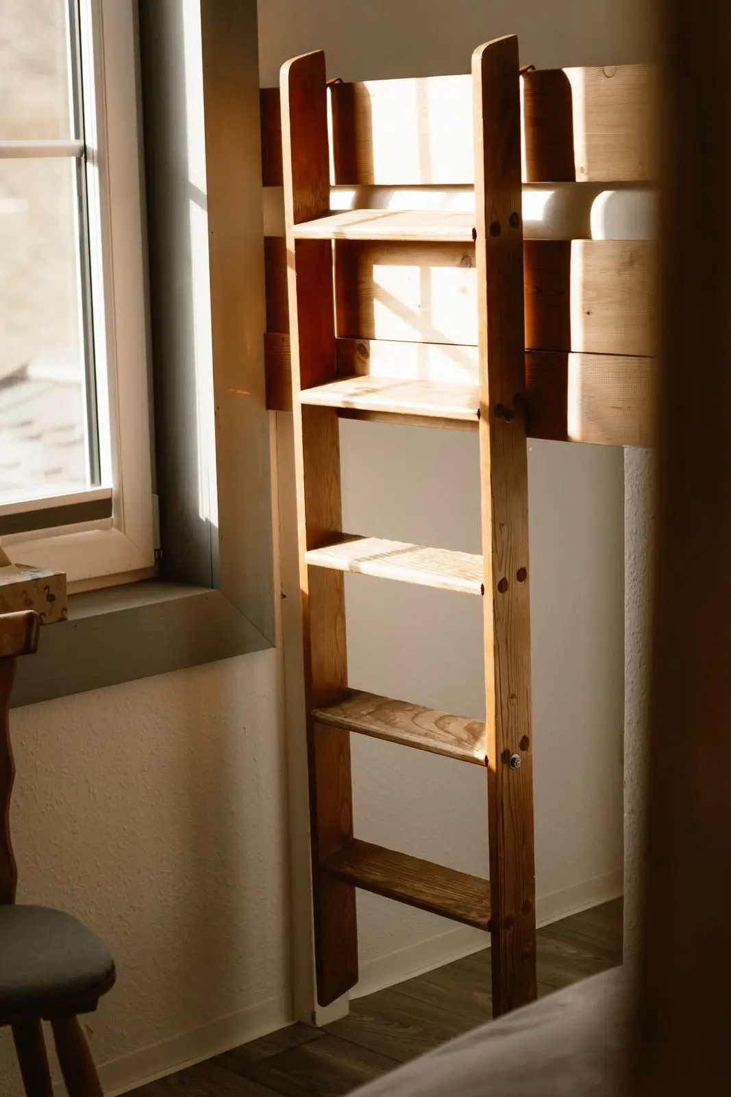 Einzelzimmer: Holzleiter zum Hochbett im Sonnenlicht