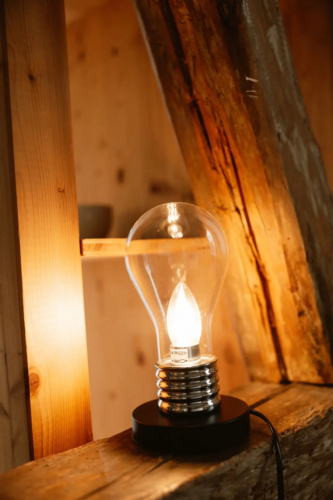 Einzelzimmer: warm leuchtende Tischlampe auf dem alten Holzbalken
