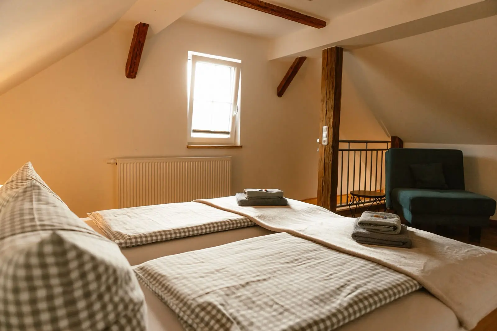 Familien-Suite: Schlafbereich unter historischen Dachbalken mit Galerie und Sessel