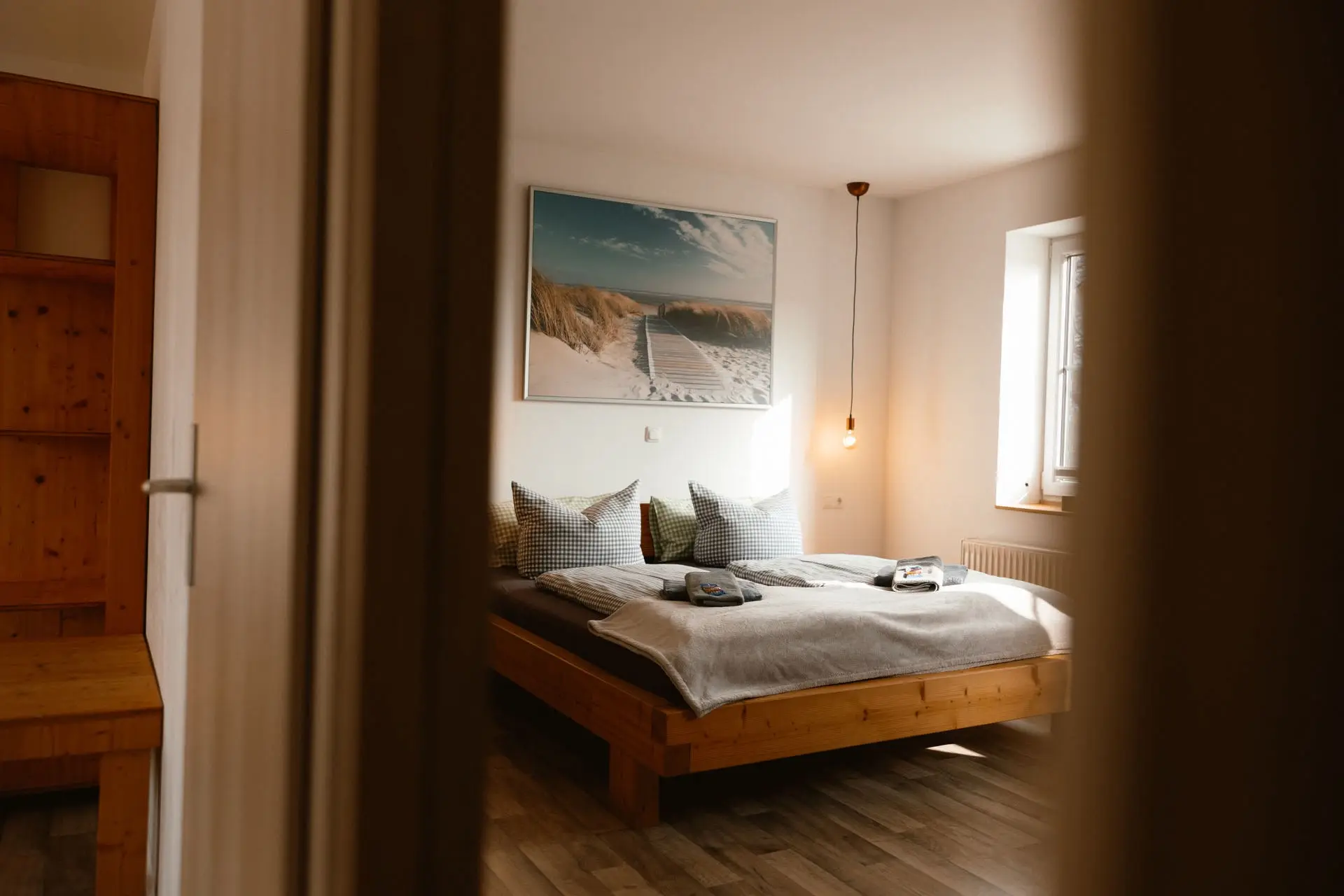 Familienzimmer: heller Schlafbereich mit zwei Betten unter dem Strandbild