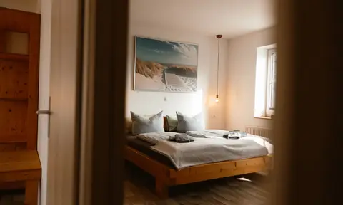 Familienzimmer: heller Schlafbereich mit zwei Betten unter dem Strandbild