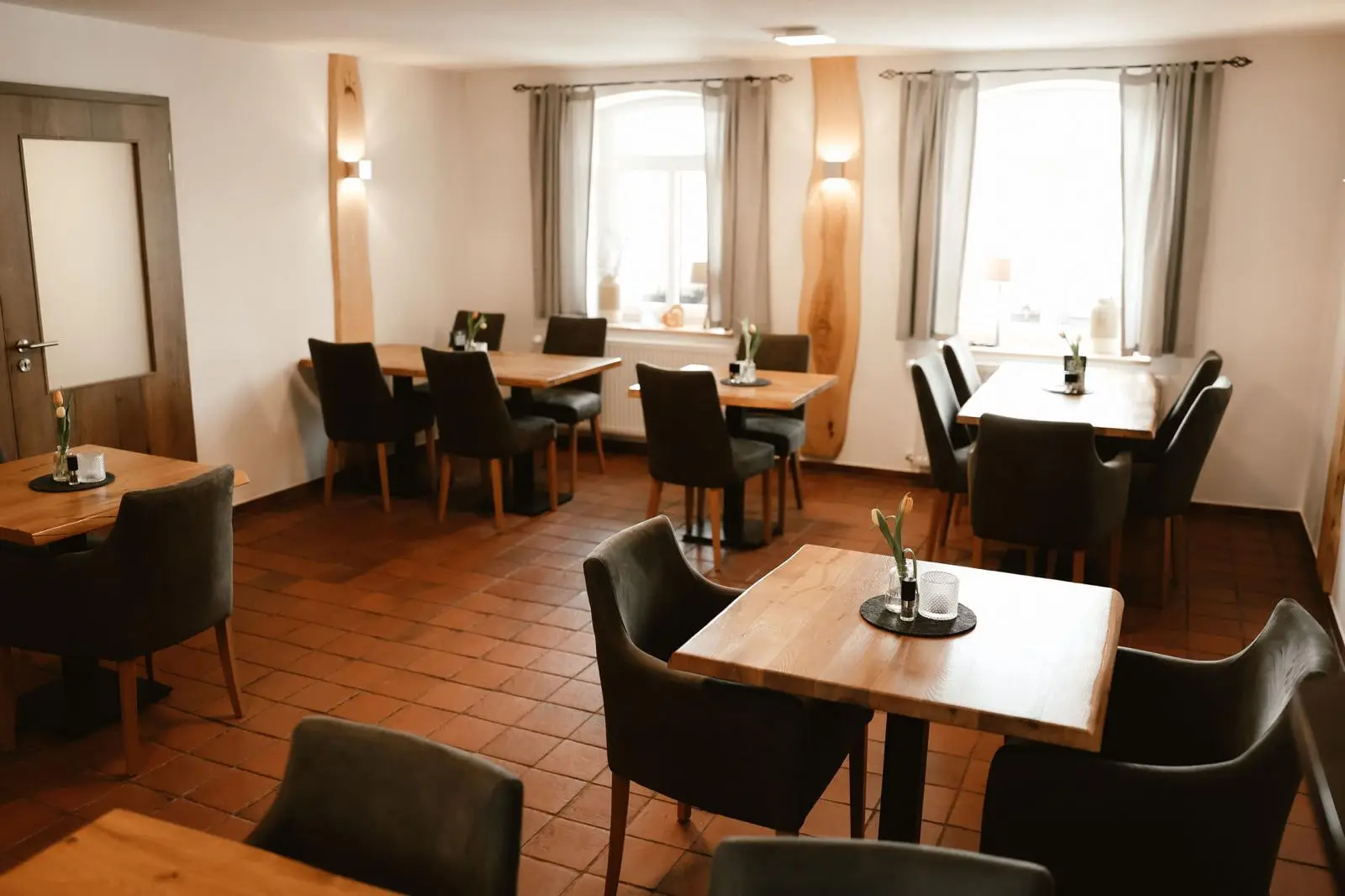 Heller Festsaal mit eingedeckten Tischen an den Fenstern